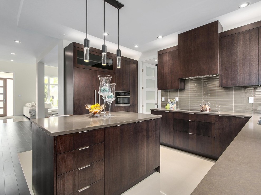 Example of a mid-sized trendy porcelain tile and beige floor kitchen design in Vancouver with an undermount sink, flat-panel cabinets, dark wood cabinets, quartz countertops, brown backsplash, glass tile backsplash, paneled appliances and an island