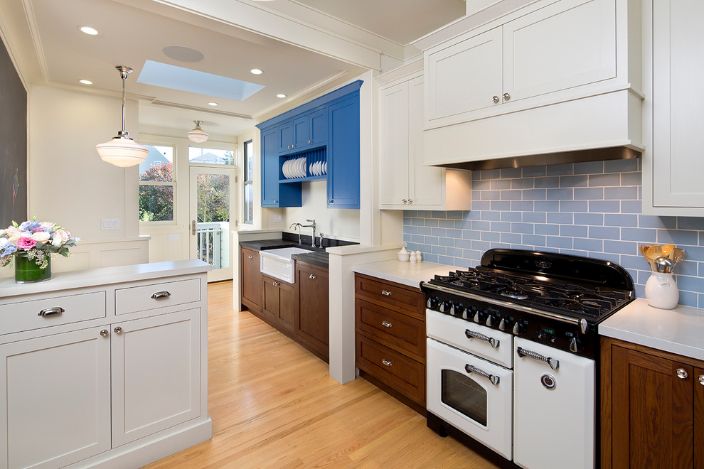 Пример оригинального дизайна: кухня в классическом стиле с обеденным столом, с полувстраиваемой мойкой (с передним бортиком), фасадами в стиле шейкер, синими фасадами, синим фартуком, фартуком из плитки кабанчик и белой техникой в частном доме