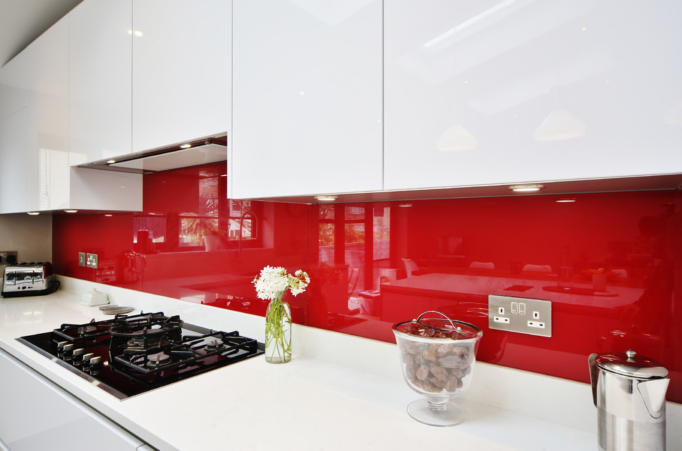 Immagine di una cucina contemporanea di medie dimensioni con lavello sottopiano, ante lisce, ante turchesi, top in quarzite, paraspruzzi rosso, paraspruzzi con lastra di vetro, parquet chiaro, pavimento marrone e top bianco