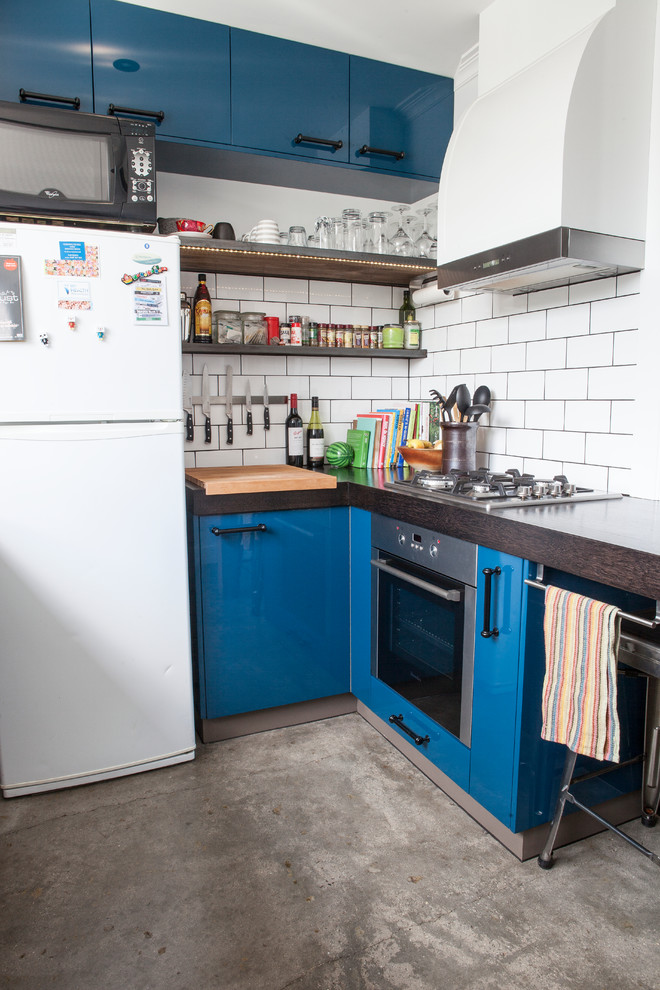 Moderne Küche mit flächenbündigen Schrankfronten, blauen Schränken, Küchenrückwand in Weiß, Rückwand aus Metrofliesen und weißen Elektrogeräten in Melbourne