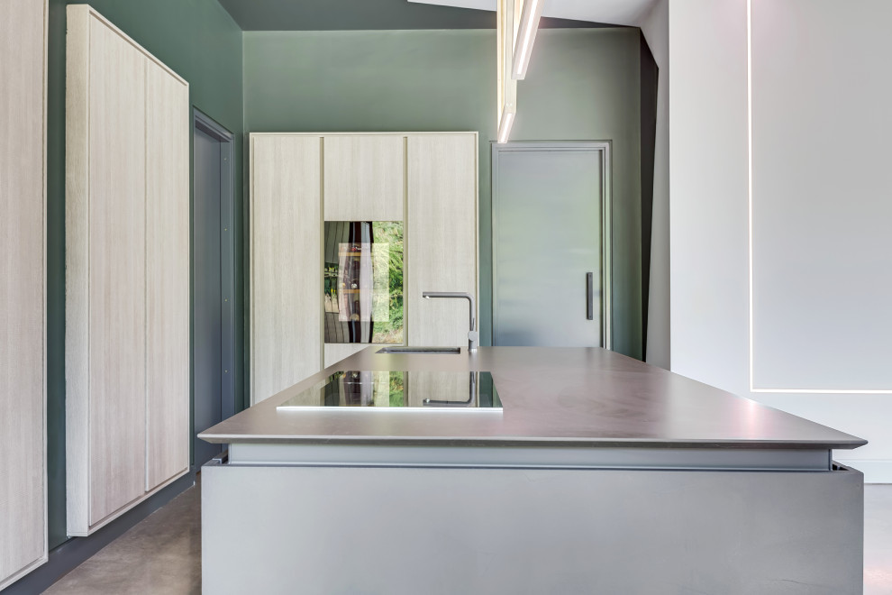 Immagine di una grande cucina moderna con lavello da incasso, ante lisce, ante in legno chiaro, top in quarzite, elettrodomestici da incasso, pavimento in cemento e top grigio