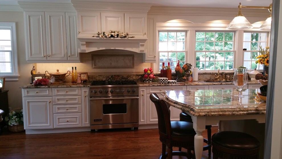 Example of a mid-sized classic u-shaped dark wood floor eat-in kitchen design in New York with an undermount sink, raised-panel cabinets, white cabinets, granite countertops, multicolored backsplash, stone slab backsplash, stainless steel appliances and an island