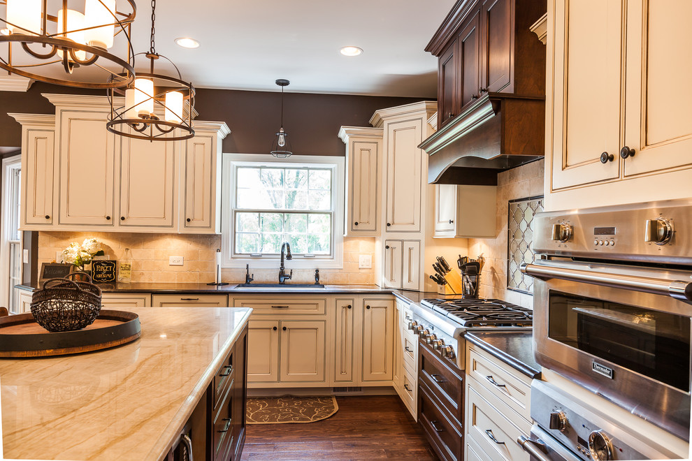 Foto di una grande cucina classica con lavello sottopiano, ante a filo, ante beige, paraspruzzi beige, pavimento in legno massello medio e pavimento marrone