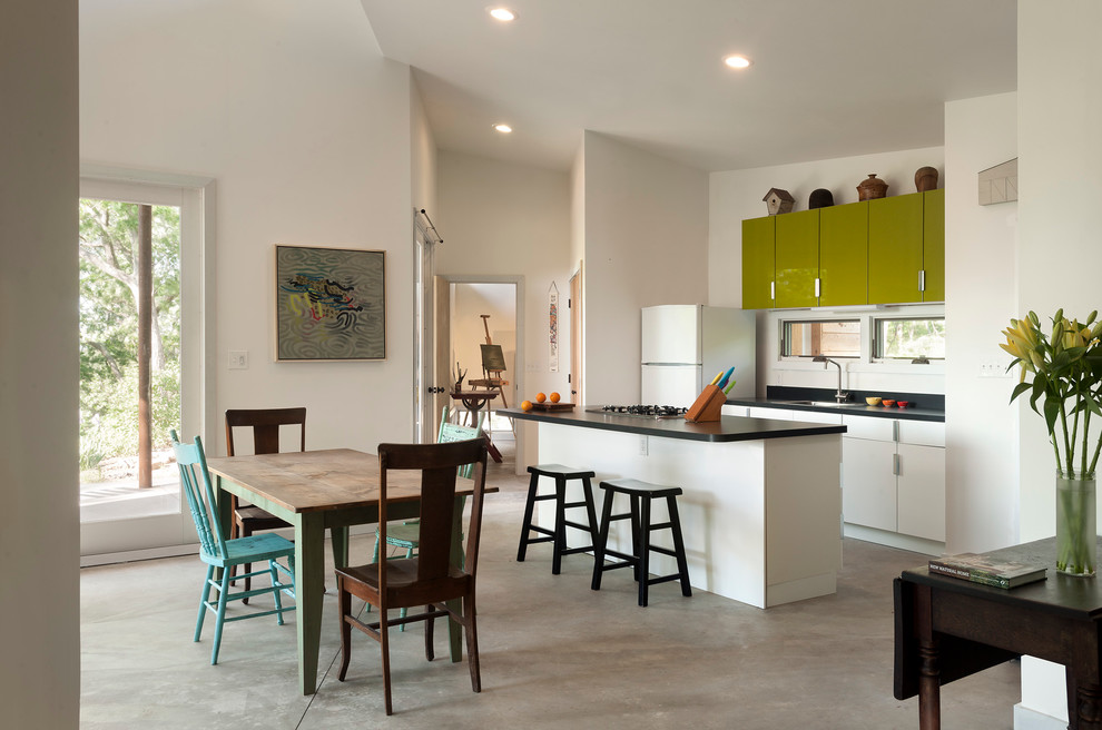 This is an example of a small contemporary galley kitchen/diner in DC Metro with a built-in sink, flat-panel cabinets, green cabinets, white appliances, laminate countertops, white splashback, concrete flooring and an island.