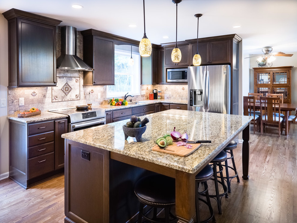 Eat-in kitchen - large mediterranean u-shaped medium tone wood floor eat-in kitchen idea in Minneapolis with a double-bowl sink, shaker cabinets, dark wood cabinets, granite countertops, stone tile backsplash, stainless steel appliances and an island