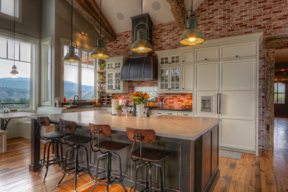 Eat-in kitchen - large cottage l-shaped brown floor and medium tone wood floor eat-in kitchen idea in Denver with a farmhouse sink, black cabinets, granite countertops, black backsplash, paneled appliances, an island, black countertops and beaded inset cabinets