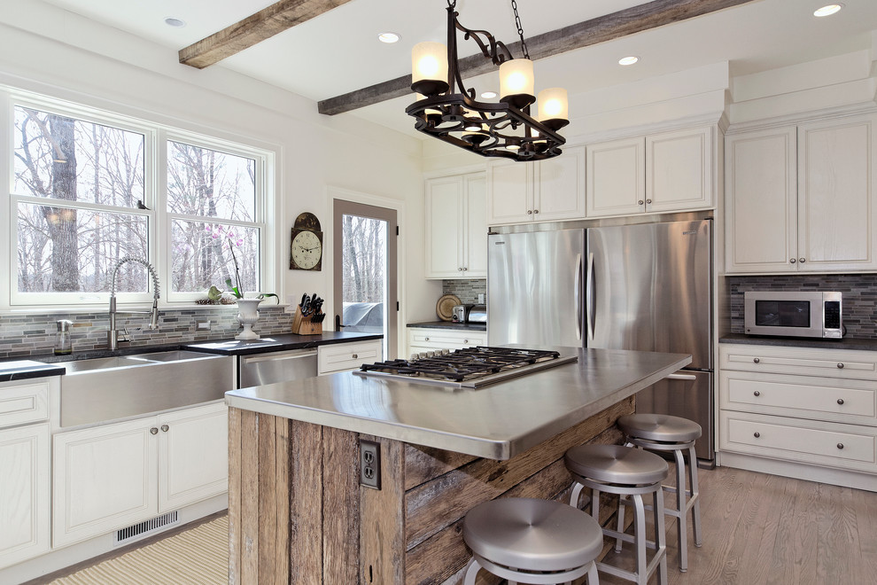 Kitchen - transitional u-shaped kitchen idea in Other with a farmhouse sink, raised-panel cabinets, white cabinets, gray backsplash, matchstick tile backsplash, stainless steel appliances and zinc countertops