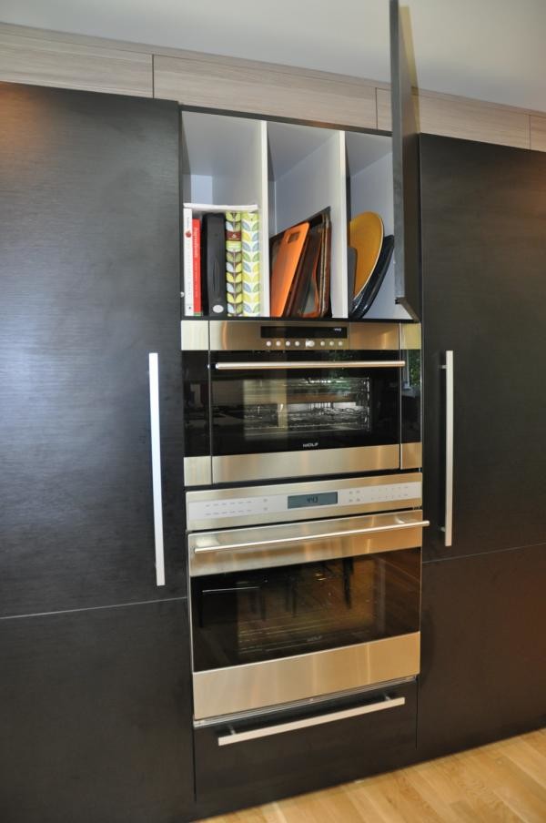 Immagine di una cucina moderna di medie dimensioni con ante lisce, ante nere, top in quarzo composito, elettrodomestici in acciaio inossidabile e parquet chiaro