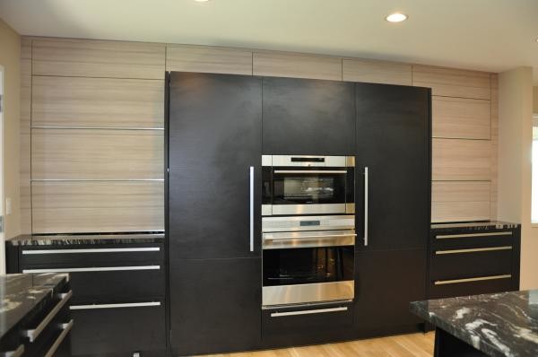 Idee per una cucina minimalista di medie dimensioni con ante lisce, ante nere, top in quarzo composito, elettrodomestici in acciaio inossidabile e parquet chiaro