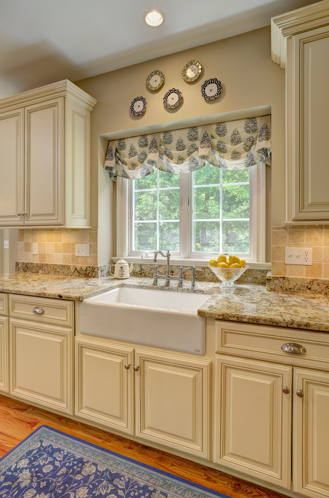 Klassisk inredning av ett mellanstort kök och matrum, med en rustik diskho, luckor med upphöjd panel, gula skåp, granitbänkskiva, gult stänkskydd, mellanmörkt trägolv och brunt golv