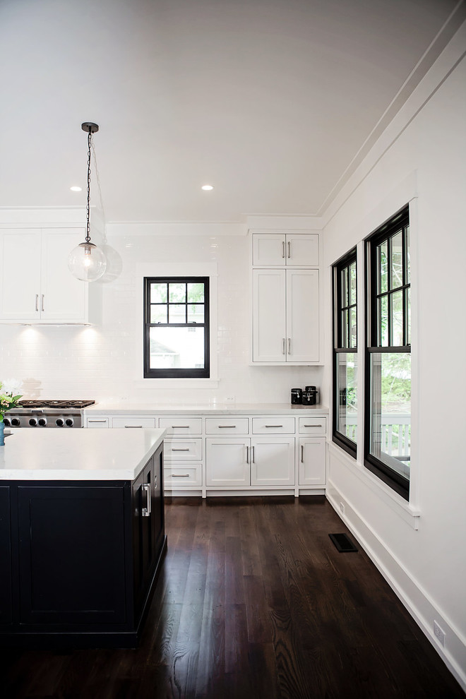 Bild på ett minimalistiskt kök, med en undermonterad diskho, vita skåp, vitt stänkskydd, stänkskydd i keramik, rostfria vitvaror, mörkt trägolv och en köksö