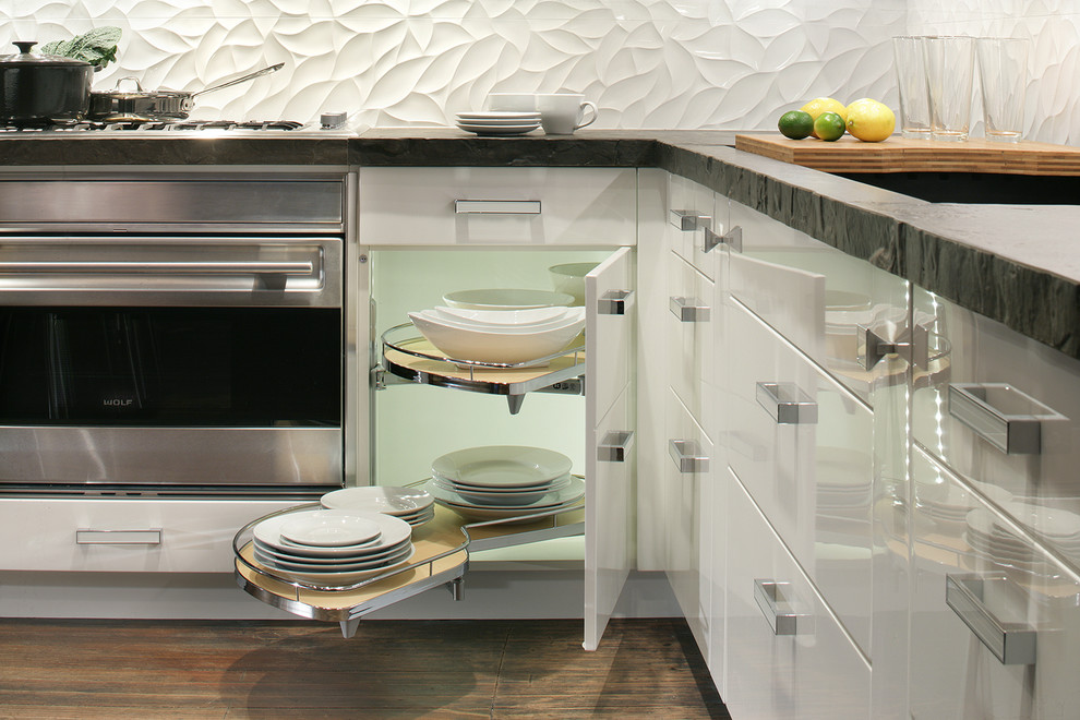 This is an example of a medium sized contemporary l-shaped kitchen/diner in New York with a submerged sink, flat-panel cabinets, brown cabinets, concrete worktops, white splashback, stainless steel appliances, medium hardwood flooring and no island.