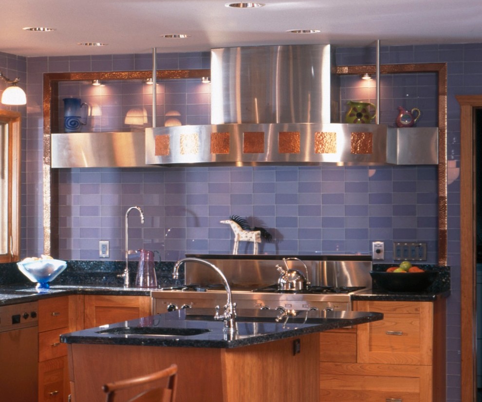 Ejemplo de cocina actual con armarios con paneles empotrados, puertas de armario de madera oscura, salpicadero azul, electrodomésticos de acero inoxidable y una isla