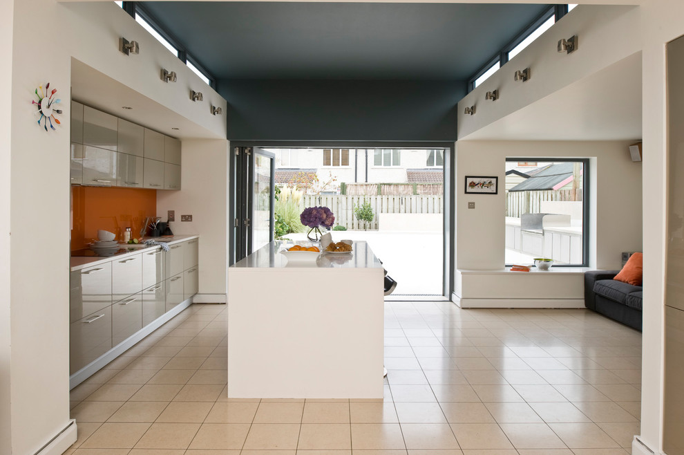 Réalisation d'une cuisine design avec un placard à porte plane, des portes de placard beiges, une crédence orange et îlot.