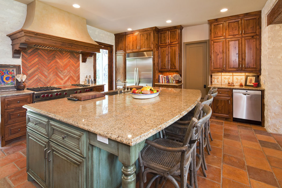 Kitchen - mediterranean kitchen idea in Austin with stainless steel appliances, raised-panel cabinets, dark wood cabinets and red backsplash