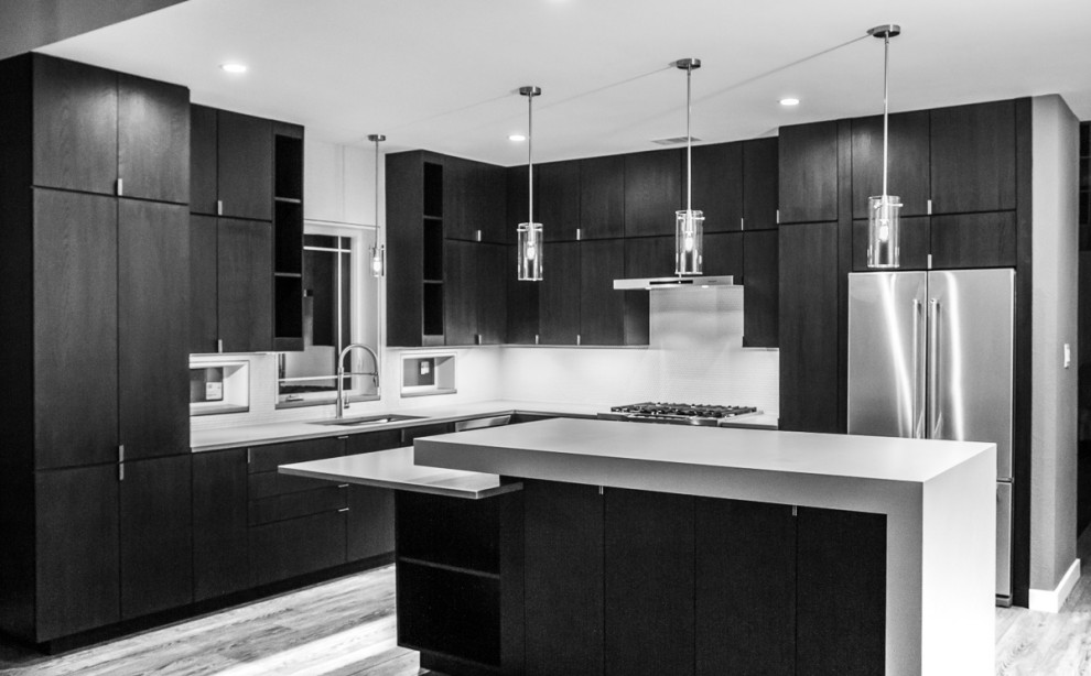 Large modern l-shaped kitchen/diner in Dallas with a belfast sink, flat-panel cabinets, black cabinets, engineered stone countertops, white splashback, ceramic splashback, stainless steel appliances, vinyl flooring, an island, grey floors and grey worktops.