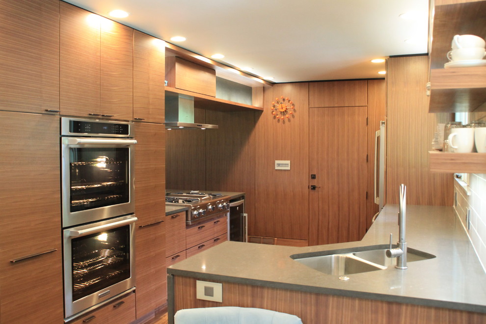 Bild på ett stort funkis kök med öppen planlösning, med en dubbel diskho, släta luckor, skåp i mellenmörkt trä, bänkskiva i kvarts, vitt stänkskydd, stänkskydd i tunnelbanekakel, rostfria vitvaror och mellanmörkt trägolv