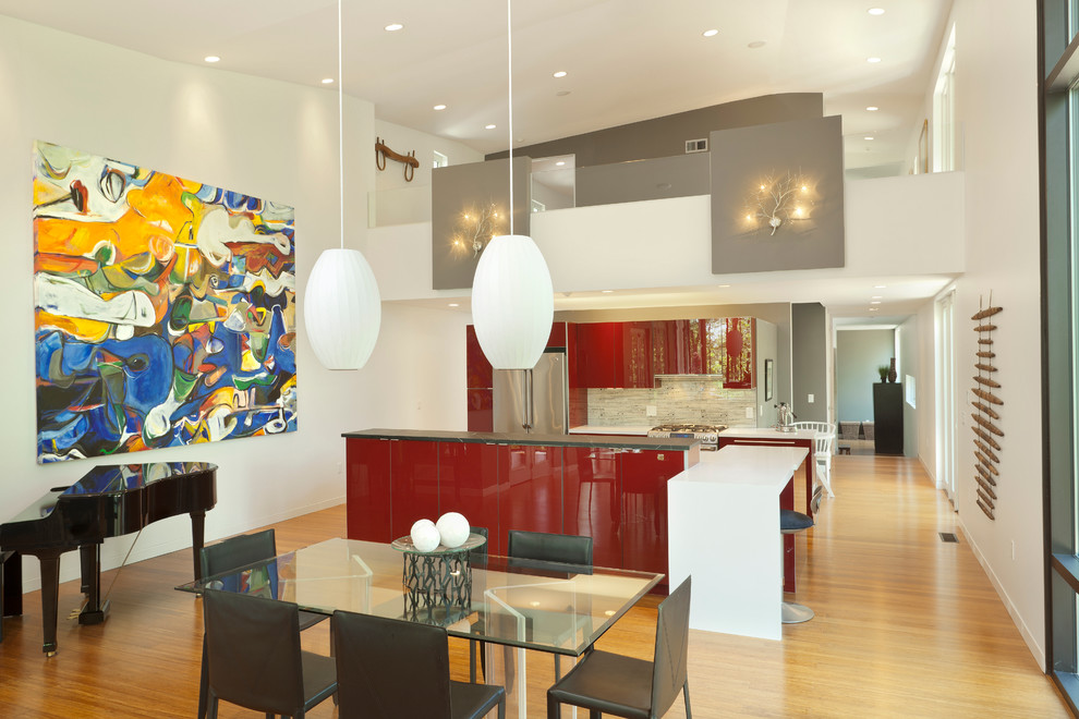 На фото: параллельная кухня в современном стиле с обеденным столом, плоскими фасадами, красными фасадами, техникой из нержавеющей стали и белым фартуком