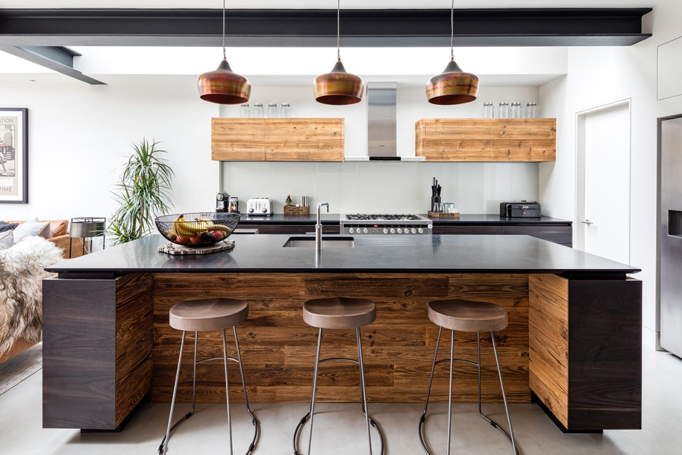 Foto på ett mellanstort funkis svart kök, med släta luckor, granitbänkskiva, glaspanel som stänkskydd, klinkergolv i porslin, en köksö, grått golv, en undermonterad diskho, skåp i mörkt trä och rostfria vitvaror