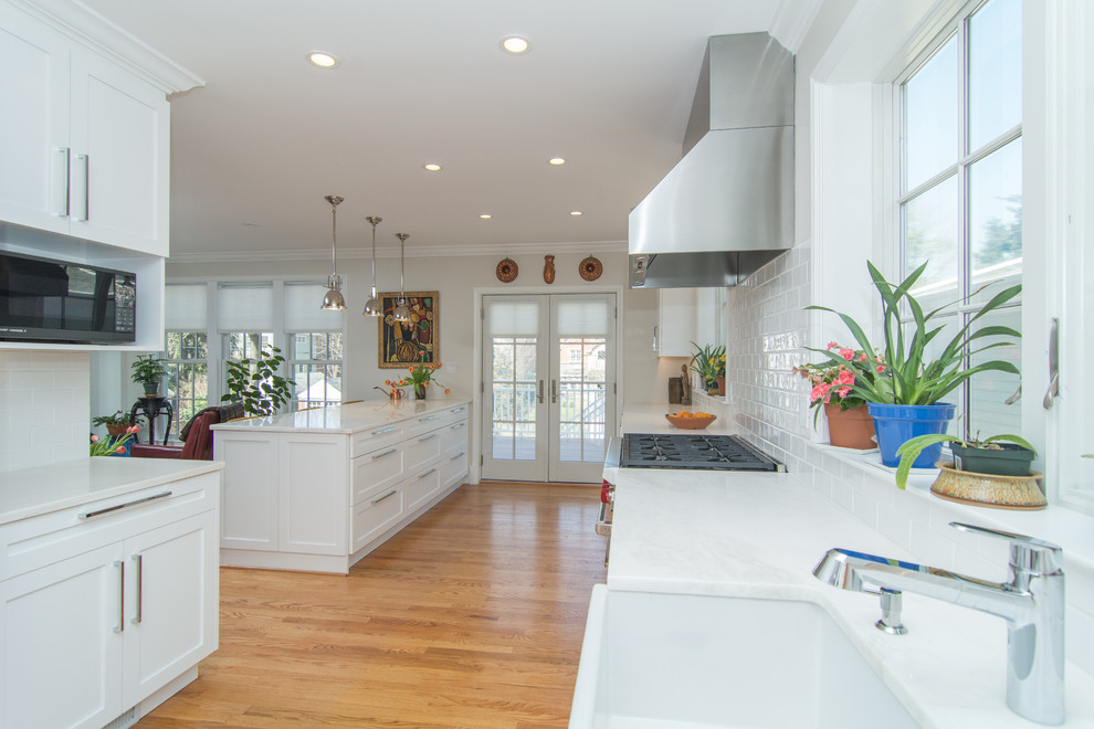Bild på ett mellanstort funkis kök, med en rustik diskho, vita skåp, marmorbänkskiva, vitt stänkskydd, stänkskydd i porslinskakel, rostfria vitvaror, mellanmörkt trägolv och en köksö