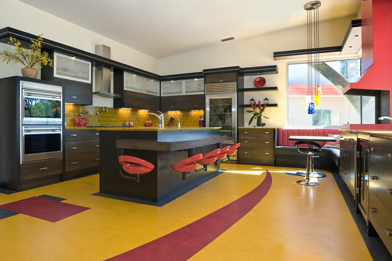 アルバカーキにある広いコンテンポラリースタイルのおしゃれなキッチン (フラットパネル扉のキャビネット、黒いキャビネット、黄色いキッチンパネル、サブウェイタイルのキッチンパネル、シルバーの調理設備、クッションフロア、アンダーカウンターシンク、ガラスカウンター、黄色いキッチンカウンター) の写真