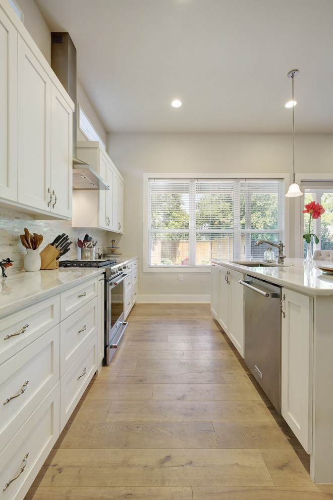 Inspiration for a mid-sized victorian light wood floor kitchen remodel in Austin with a single-bowl sink, shaker cabinets, white cabinets, marble countertops, gray backsplash, stone tile backsplash, stainless steel appliances and an island