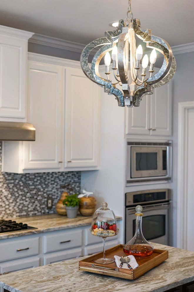 Exempel på ett mellanstort klassiskt brun brunt kök med öppen planlösning, med luckor med upphöjd panel, vita skåp, granitbänkskiva, grått stänkskydd, stänkskydd i glaskakel, rostfria vitvaror och en köksö