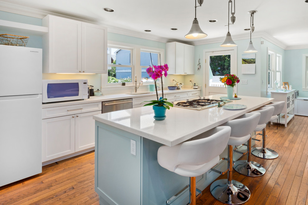Inspiration for a mid-sized coastal galley medium tone wood floor and brown floor open concept kitchen remodel in Other with a single-bowl sink, shaker cabinets, turquoise cabinets, quartz countertops, white backsplash, stainless steel appliances, an island and white countertops