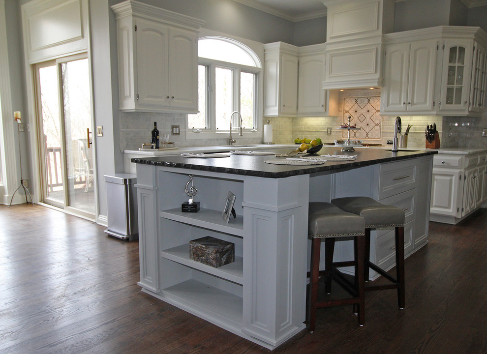 Idee per un cucina con isola centrale classico con paraspruzzi in marmo, elettrodomestici in acciaio inossidabile, parquet scuro e pavimento marrone