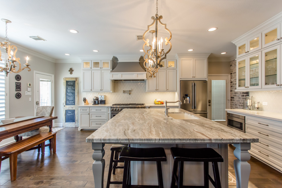 Inredning av ett klassiskt stort flerfärgad flerfärgat kök, med en undermonterad diskho, luckor med infälld panel, vita skåp, granitbänkskiva, vitt stänkskydd, stänkskydd i keramik, rostfria vitvaror, mörkt trägolv, en köksö och brunt golv