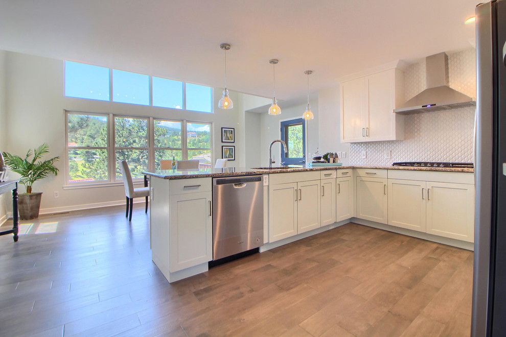 Example of a mid-sized trendy l-shaped medium tone wood floor open concept kitchen design in Denver with a double-bowl sink, shaker cabinets, white cabinets, granite countertops, white backsplash, cement tile backsplash, stainless steel appliances and an island