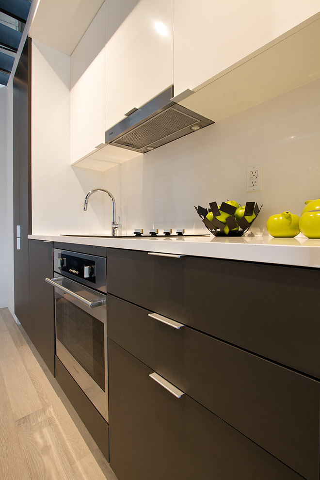 Einzeilige, Kleine Moderne Wohnküche mit flächenbündigen Schrankfronten, grauen Schränken, Küchenrückwand in Weiß, Küchengeräten aus Edelstahl, hellem Holzboden, Unterbauwaschbecken und weißer Arbeitsplatte in Toronto