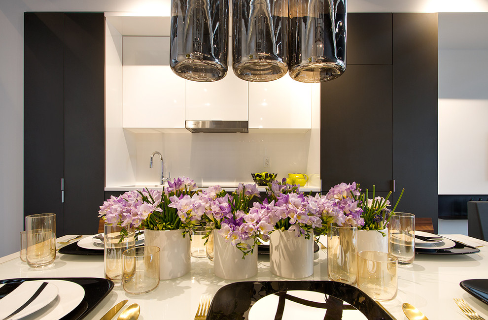 Immagine di una piccola cucina design con ante lisce, ante grigie, paraspruzzi bianco, elettrodomestici in acciaio inossidabile, parquet chiaro, lavello sottopiano e top bianco