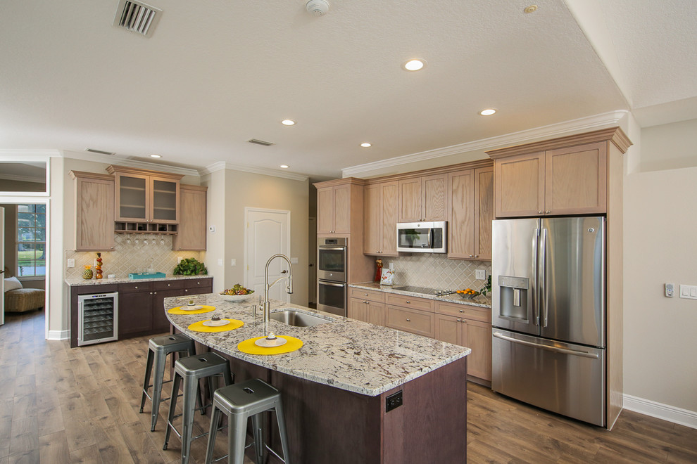 Klassische Küche mit hellen Holzschränken, Granit-Arbeitsplatte, Küchenrückwand in Beige, Küchengeräten aus Edelstahl, braunem Holzboden, Kücheninsel und braunem Boden in Tampa