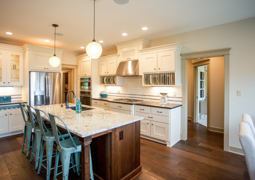 Example of a mid-sized country l-shaped medium tone wood floor eat-in kitchen design in Orange County with a double-bowl sink, shaker cabinets, white cabinets, granite countertops, white backsplash, subway tile backsplash, stainless steel appliances and an island