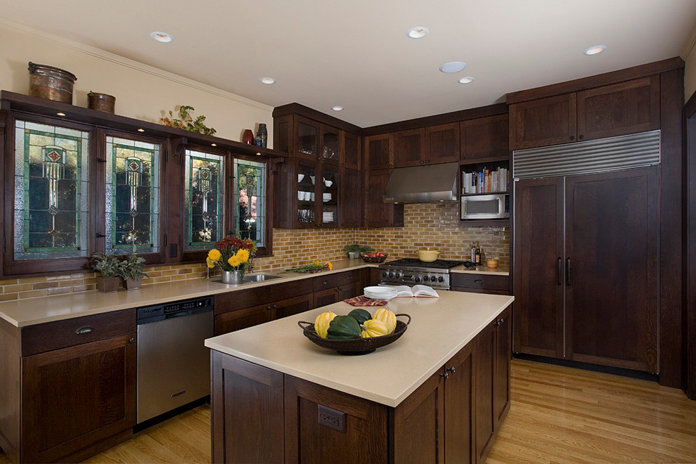 Ejemplo de cocina tradicional con armarios estilo shaker, puertas de armario de madera en tonos medios, salpicadero beige y electrodomésticos con paneles
