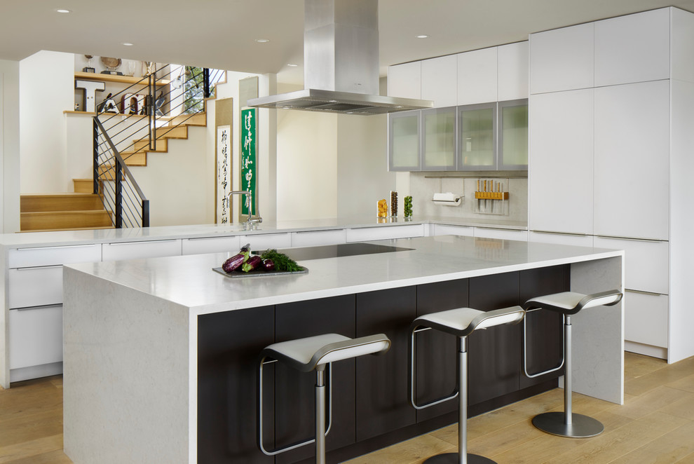 На фото: кухня в современном стиле с плоскими фасадами, белыми фасадами, светлым паркетным полом и островом с