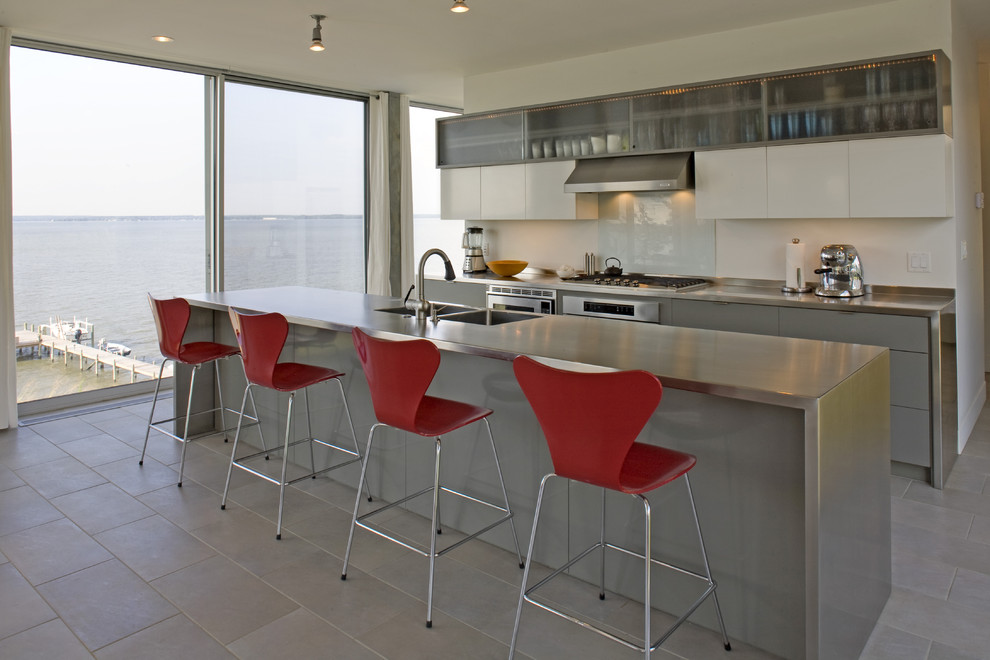 Kitchen - modern galley kitchen idea in Baltimore with stainless steel countertops, gray cabinets, an integrated sink, glass sheet backsplash, flat-panel cabinets, white backsplash and stainless steel appliances