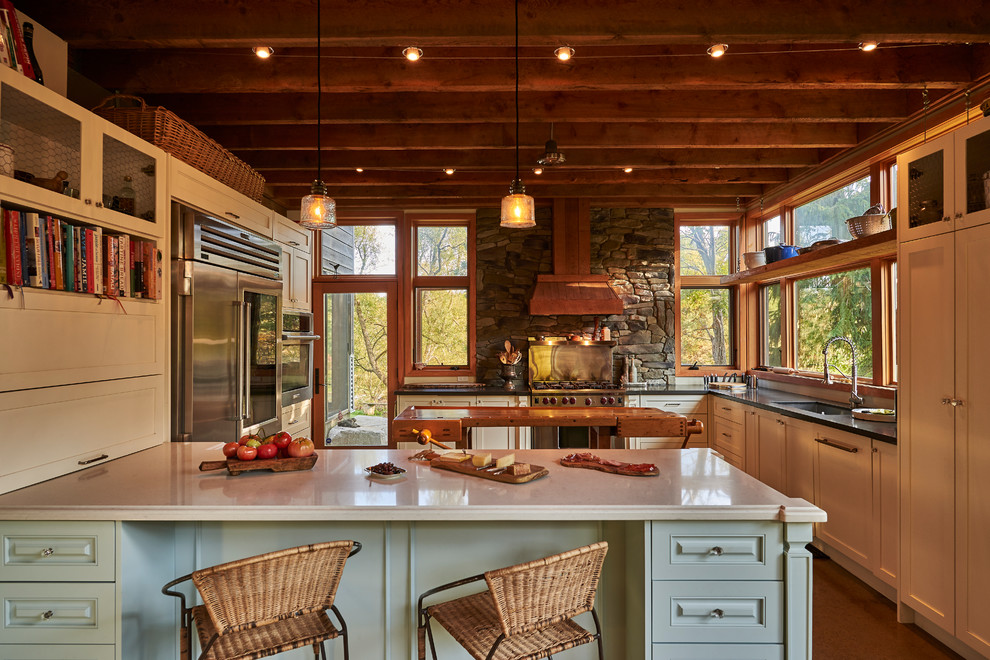 Bild på ett stort rustikt kök, med en undermonterad diskho, skåp i shakerstil, vita skåp, bänkskiva i kvartsit, rostfria vitvaror, en halv köksö och brunt golv