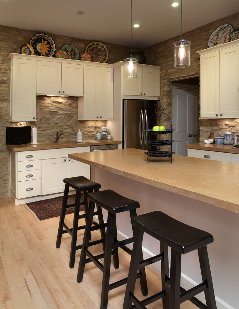Immagine di una cucina stile rurale con elettrodomestici in acciaio inossidabile, ante in stile shaker, ante bianche, top in cemento, paraspruzzi marrone e struttura in muratura