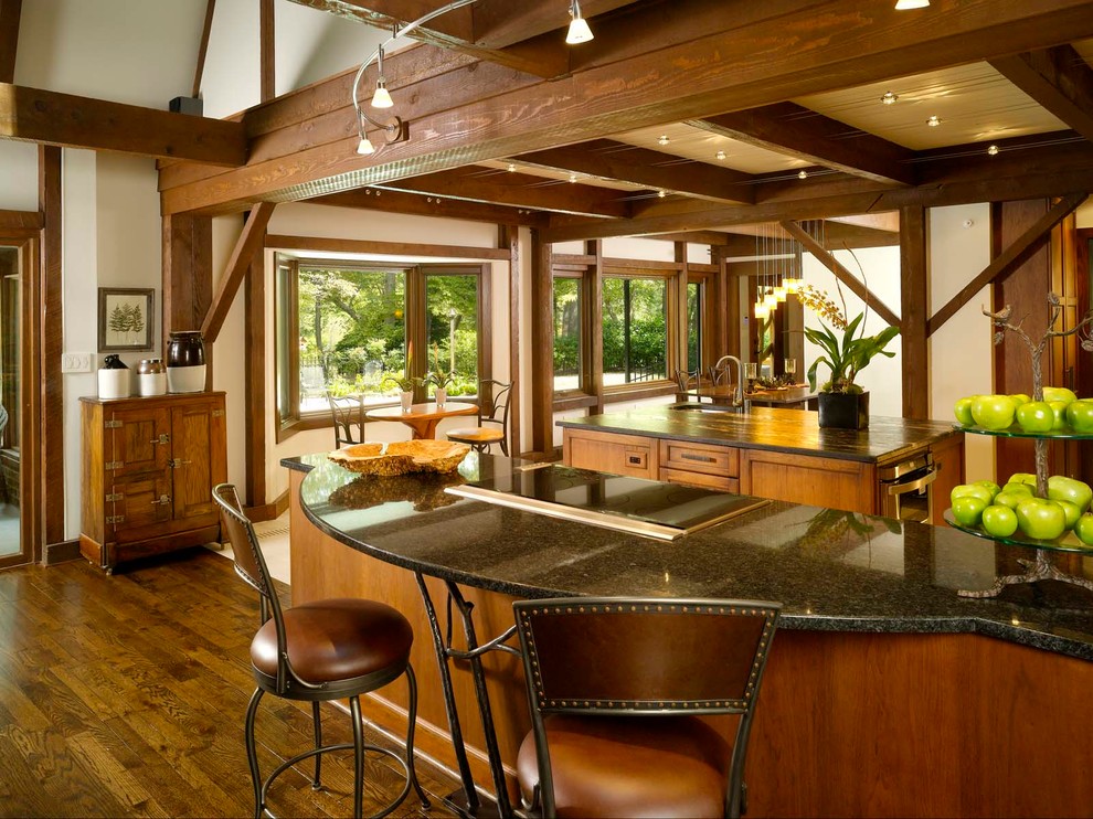 This is an example of a large rustic single-wall kitchen/diner in Atlanta with a submerged sink, an island, recessed-panel cabinets, dark wood cabinets, engineered stone countertops, black splashback, stone slab splashback, integrated appliances and dark hardwood flooring.