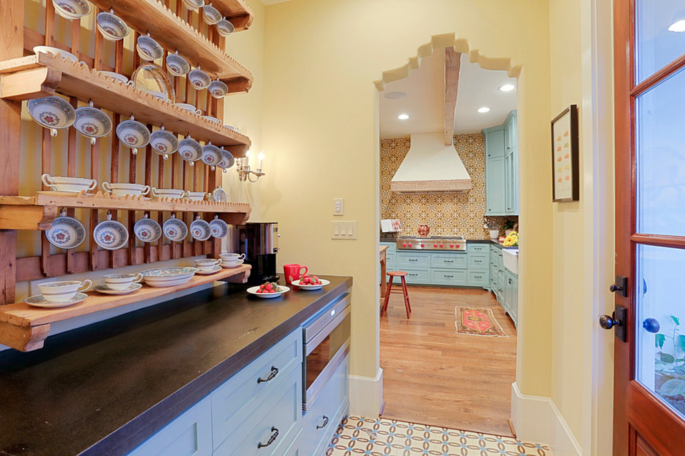 This is an example of a small mediterranean kitchen pantry in Houston with shaker cabinets, blue cabinets, granite worktops, stainless steel appliances and concrete flooring.
