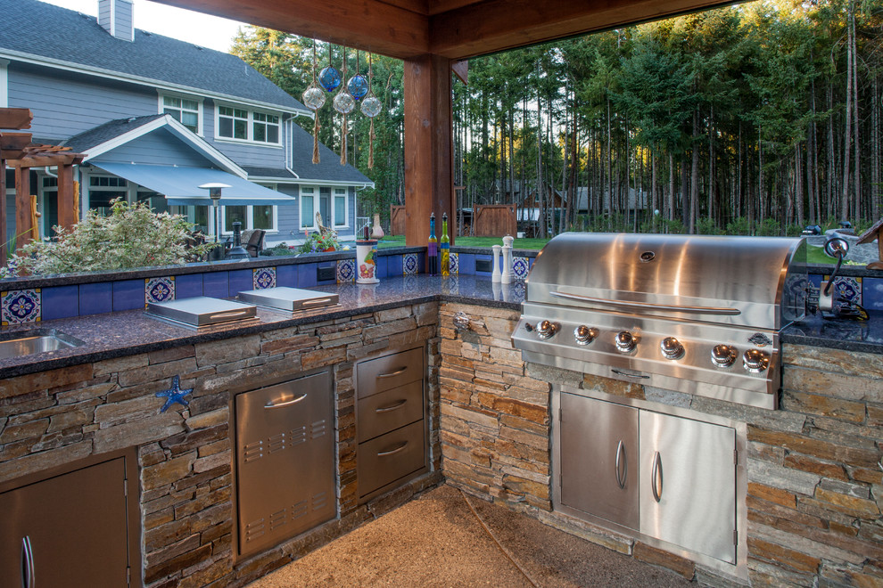 Foto på ett rustikt kök, med en undermonterad diskho, skåp i rostfritt stål, granitbänkskiva, blått stänkskydd, stänkskydd i terrakottakakel, rostfria vitvaror och betonggolv