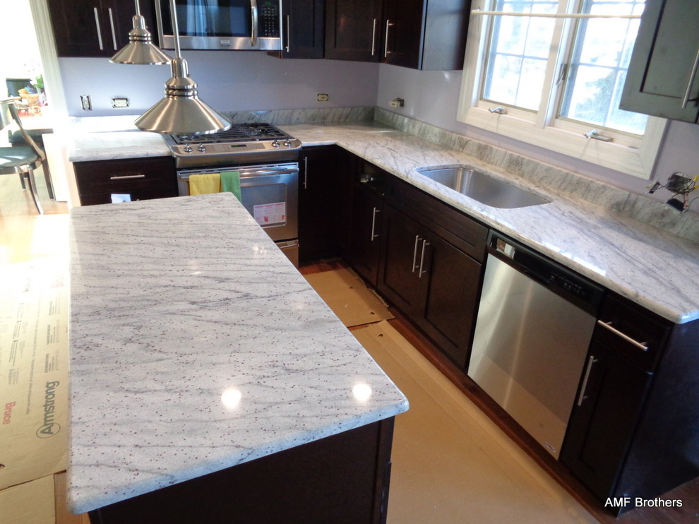 Immagine di una cucina minimalista con lavello a doppia vasca e top in granito
