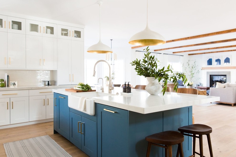 Inspiration for a large transitional l-shaped medium tone wood floor open concept kitchen remodel in Salt Lake City with a farmhouse sink, shaker cabinets, white backsplash, subway tile backsplash, stainless steel appliances and an island