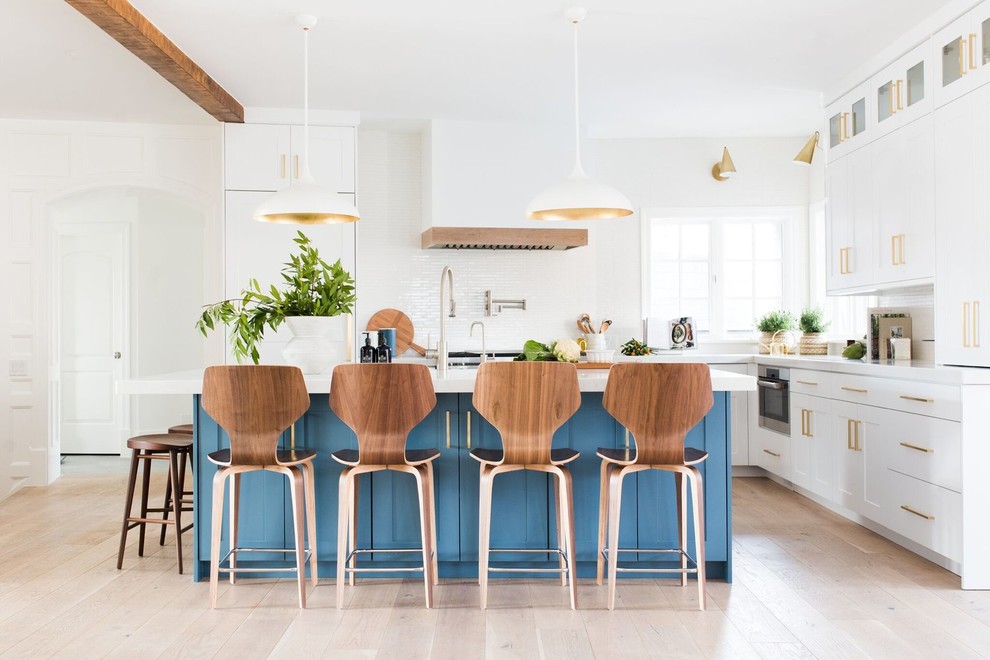 Example of a large transitional l-shaped light wood floor and beige floor kitchen design in Salt Lake City with shaker cabinets, white backsplash, an island, white cabinets and white countertops