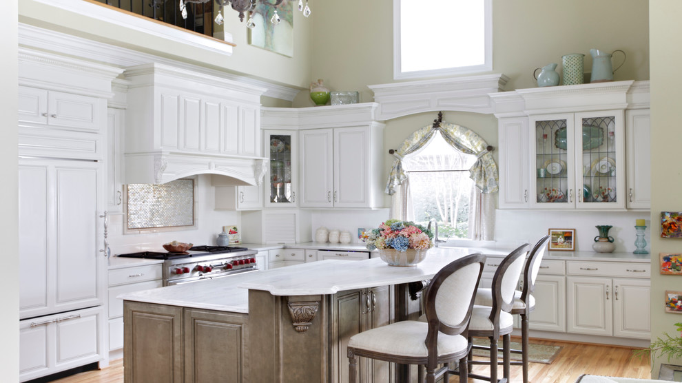 Example of a large farmhouse l-shaped light wood floor and beige floor eat-in kitchen design in Birmingham with a double-bowl sink, raised-panel cabinets, white cabinets, marble countertops, white backsplash, mosaic tile backsplash, paneled appliances and an island