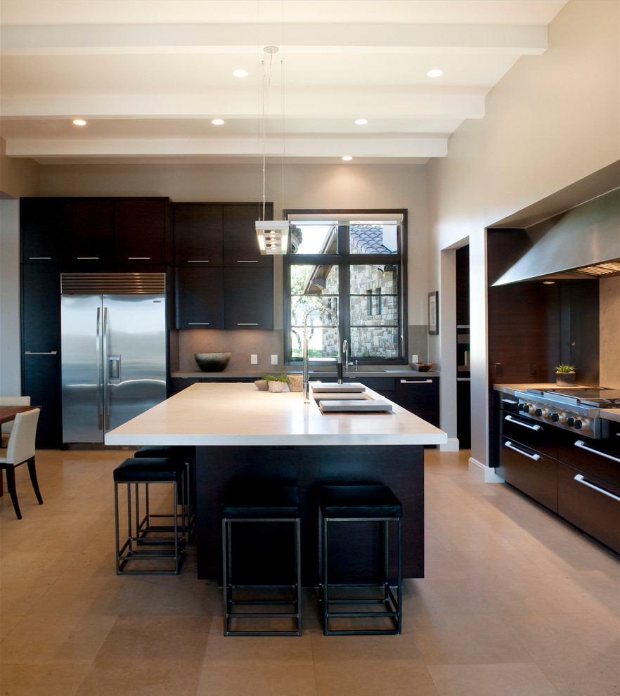 This is an example of a large contemporary l-shaped kitchen/diner in Austin with a submerged sink, flat-panel cabinets, dark wood cabinets, marble worktops, beige splashback, stone slab splashback, stainless steel appliances, travertine flooring, an island and beige floors.