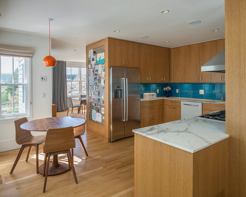 Example of a minimalist u-shaped light wood floor kitchen design in New York with an undermount sink, flat-panel cabinets, medium tone wood cabinets, marble countertops, blue backsplash, cement tile backsplash, stainless steel appliances and no island