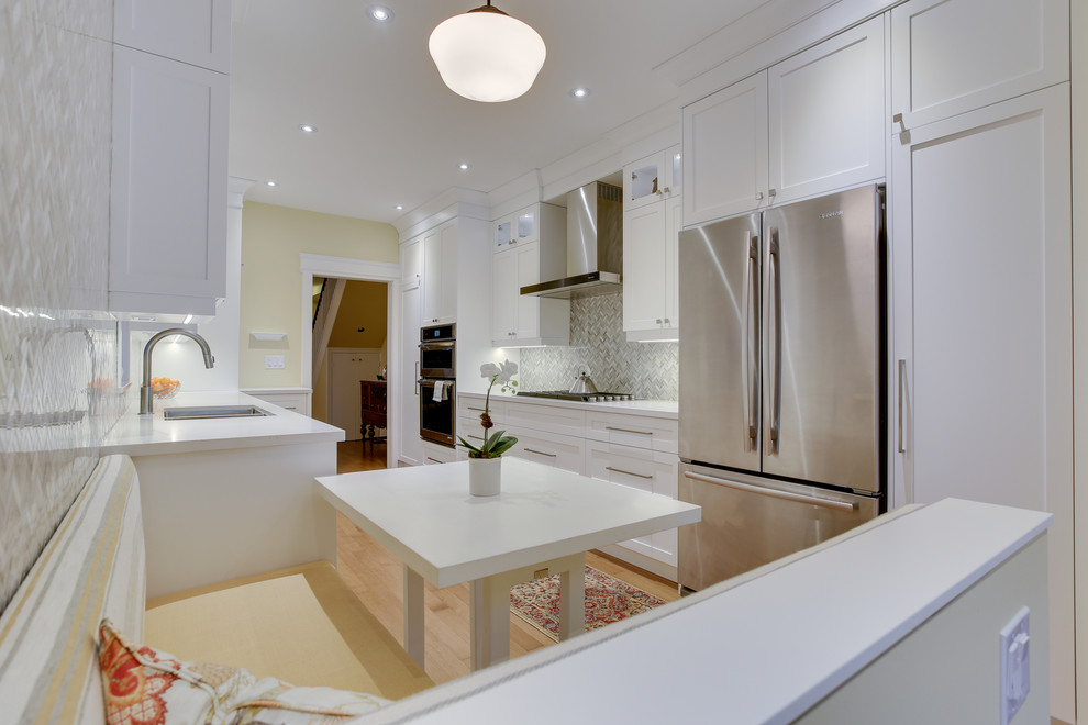 Photo of a medium sized classic galley kitchen in Toronto with a submerged sink, shaker cabinets, white cabinets, engineered stone countertops, grey splashback, stone tiled splashback, stainless steel appliances, medium hardwood flooring and no island.